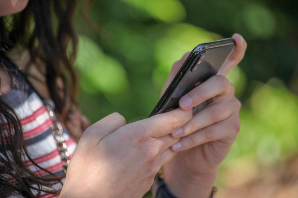 Foto de una figura femenina revisando su celular.